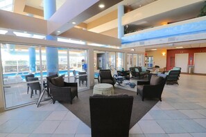 A spacious indoor area with a pool view, large windows, and multiple seating areas. - 2-bdrm, 2 full bath, kitchen, ocean view unit w/balcony - steps from the beach. (Virginia Beach)