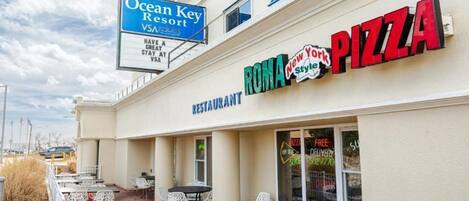 Restaurante chamado 'ROMA New York Style Pizza' com área externa e um aviso para 'Ocean Key Resort' ao fundo.