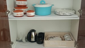 A kitchen cabinet with various cookware and utensils.