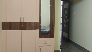 A room with a wardrobe, a mirror, and a door with a decorative panel.