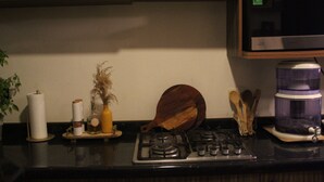 Een keuken met een gasfornuis, een magnetron en diverse keukengerei op het aanrecht.