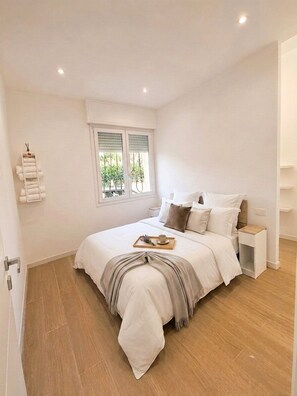 A bedroom with a bed, bedside tables, a window, and a towel rack. - In DhomeU Tua (Selargius)
