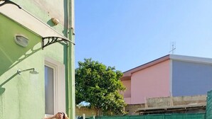 Un patio con una mesa y sillas, una persona en traje de baño y un grupo de personas sentadas en un sofá.
