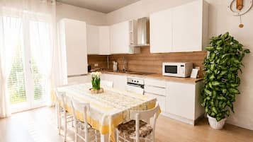 Une cuisine moderne avec des meubles blancs, un plan de travail en bois et un coin repas comprenant une table et des chaises.