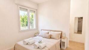 Un dormitorio con cama, mesitas de noche, una ventana y un espejo.