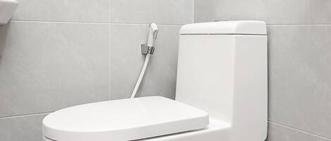 Un inodoro blanco en un baño con azulejos grises en las paredes y el suelo.