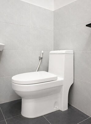 Un inodoro blanco en un baño con azulejos grises en las paredes y el suelo.