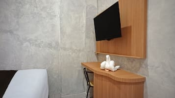 A hotel room with a bed, a wooden counter, a chair, and a mounted television.