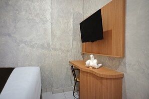 A hotel room with a bed, a wooden counter, a chair, and a mounted television. - Hotel O near Universitas Sumatera Utara  (Medan)