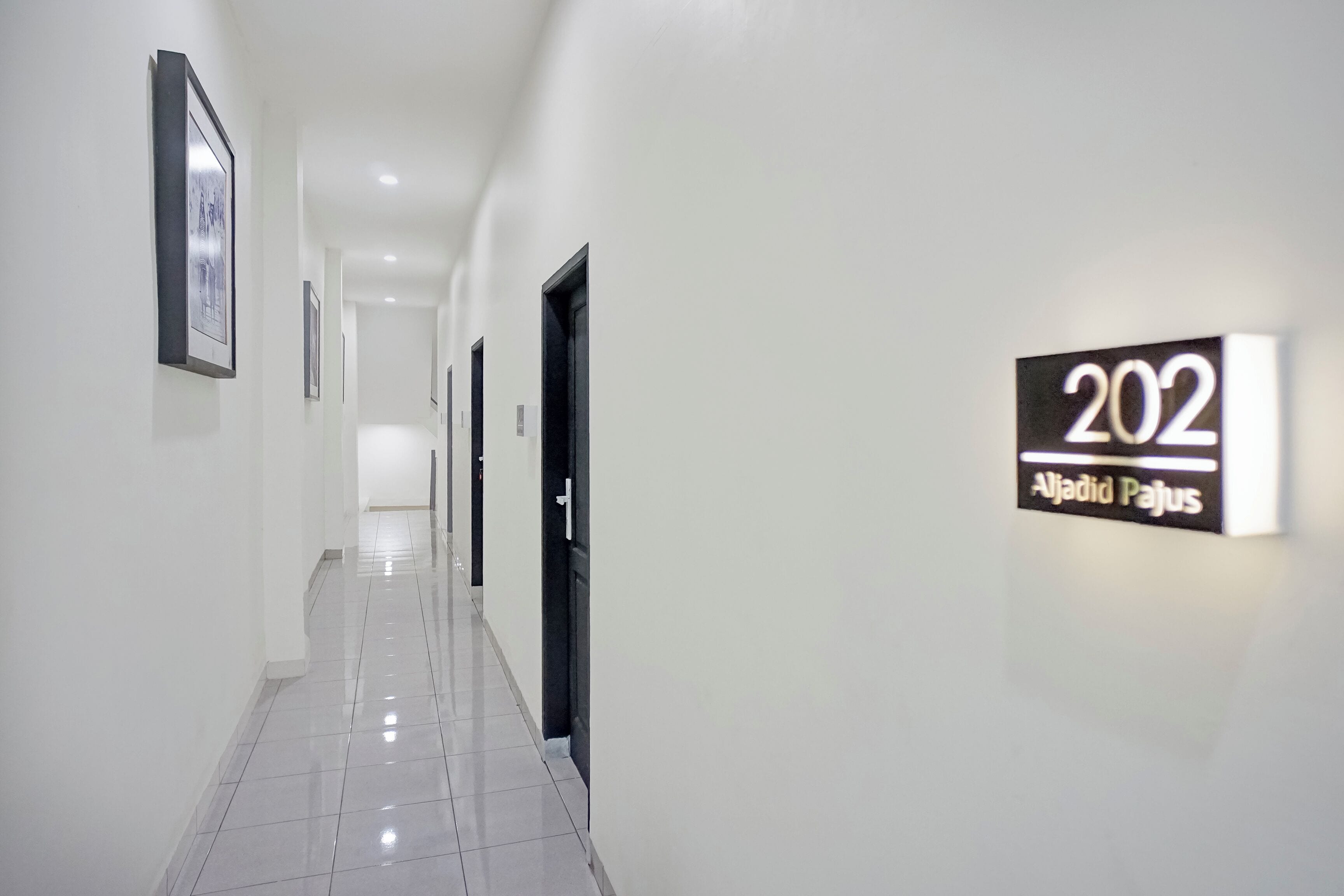 A corridor with a sign indicating room number 202 and the name 'Aljadid Pajus'.