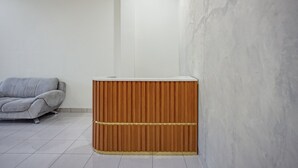 A room with a grey sofa, a wooden cabinet, and a white wall. - Hotel O near Universitas Sumatera Utara  (Medan)