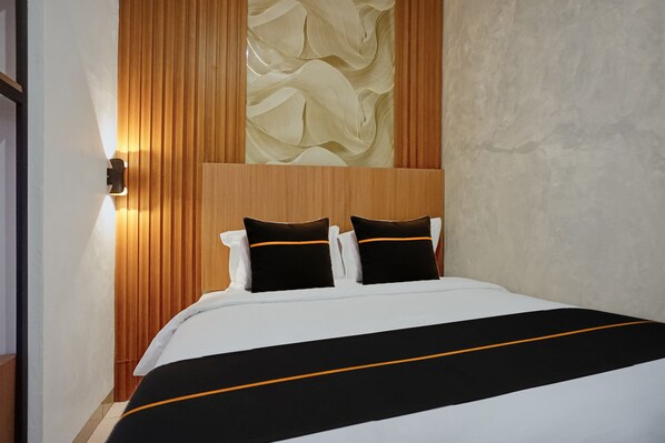 Habitación de hotel con una cama, cabecero de madera y una pared con diseño texturizado.