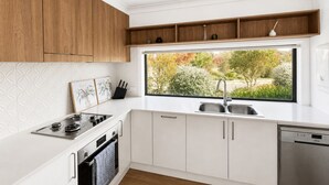 A modern kitchen with white cabinetry, a stainless steel sink, a built-in oven, and a dishwasher.
