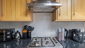Una cucina con mobili in legno, una cappa in acciaio inossidabile, un piano cottura a gas, una macchina da caffè e un tostapane.