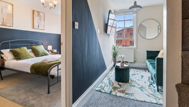 Una camera da letto moderna con un letto, una scrivania, una sedia, una finestra vista edifici e una scala.