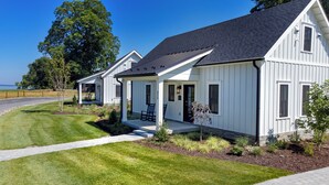 A row of white single-story houses with dark roofs, a paved driveway, and a grassy lawn.