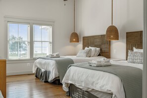 Un dormitorio con dos camas, un ventanal grande y una lámpara colgante.