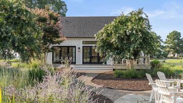 A modern house with a large front porch, a well-maintained garden, and outdoor seating.