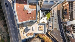 An aerial view of a modern building with a rooftop terrace, a parking area, and adjacent high-rise structures. - Apex Executive Apartments- The Ironworks (Dublin)