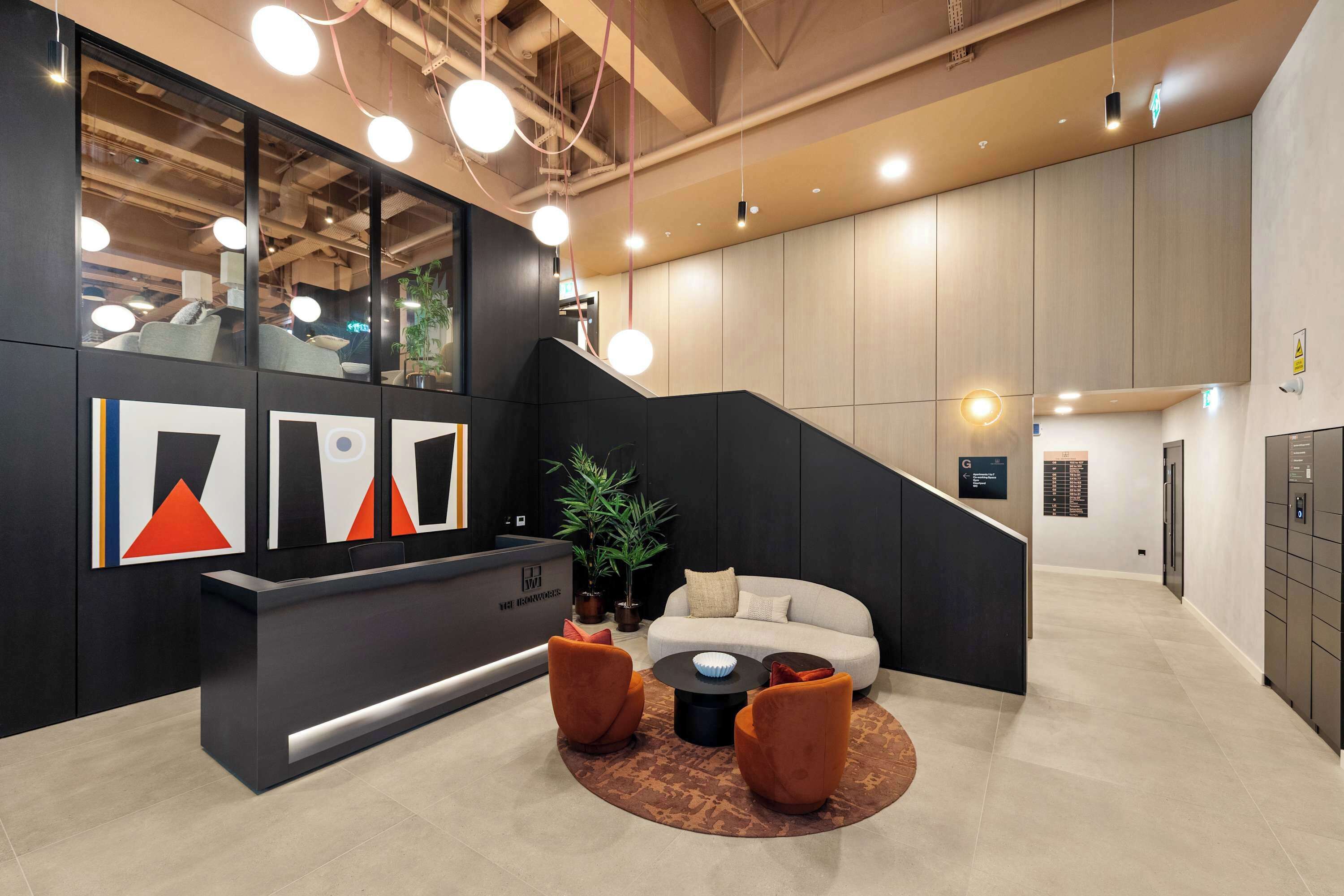 A modern reception area with a black desk, a white sofa, and orange chairs.