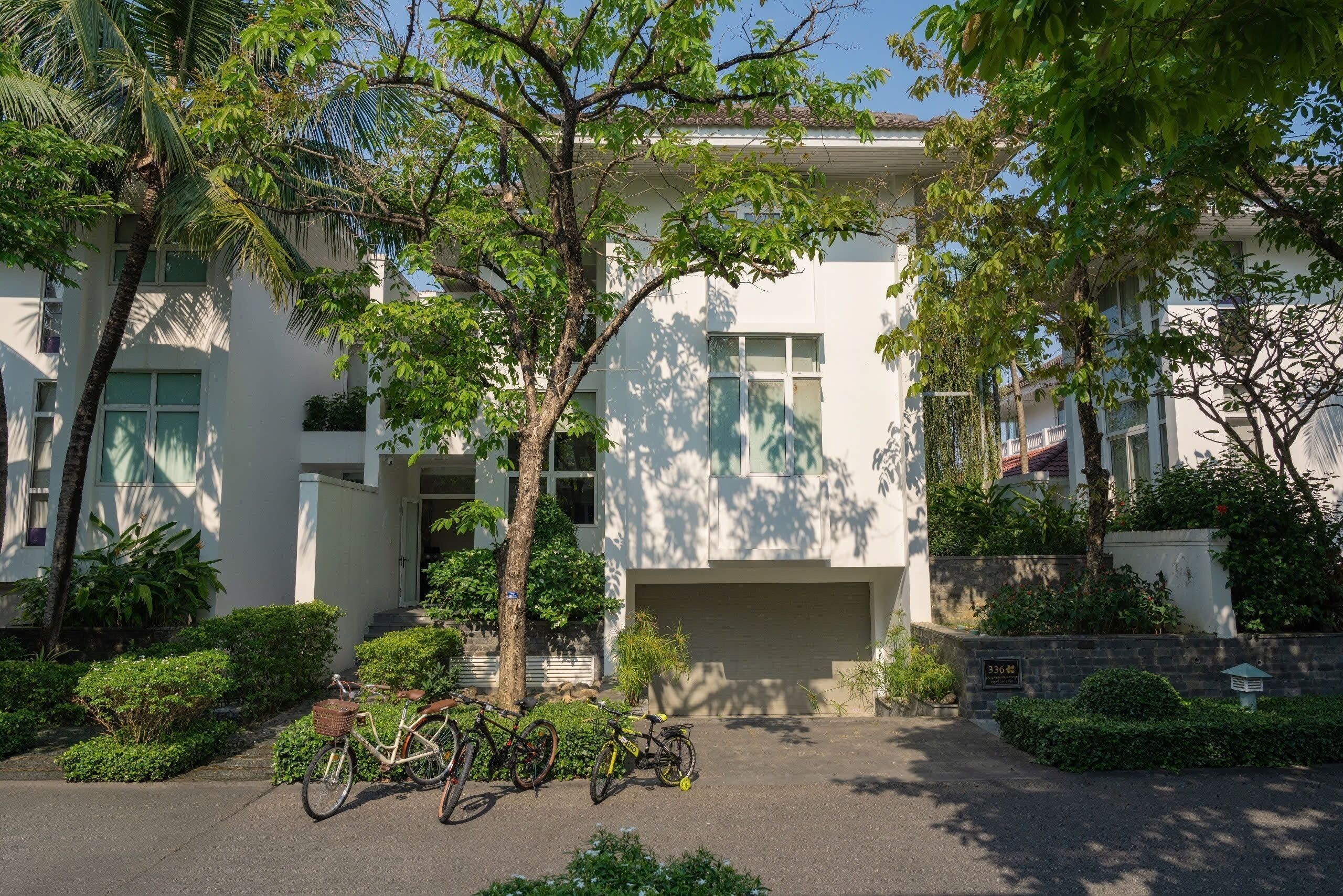 A modern building with a garage, surrounded by greenery and trees.