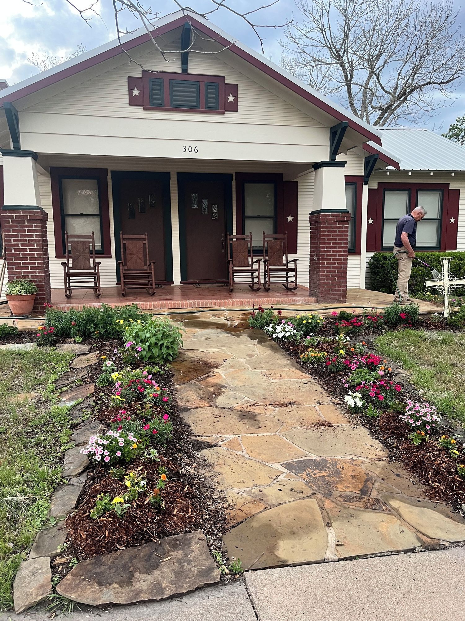 A house with a stone pathway leading to the front door, surrounded by flower beds.