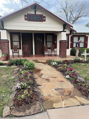 A house with a stone pathway leading to the front door, surrounded by flower beds.