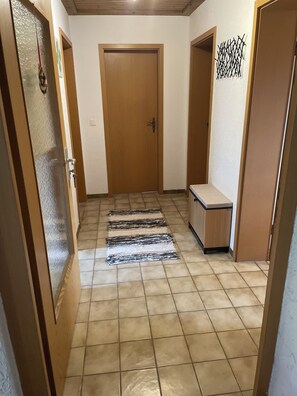 A hallway with a wooden door, a bench, and a patterned rug. - Quiet apartment in the countryside with balcony (Weiding)