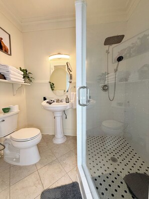 Ein Badezimmer mit Toilette, Waschtisch und einer Duschkabine.