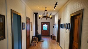 A hallway with wooden floors, a chandelier, framed pictures, and a door with a stained glass window. - Welcoming 2-bedroom house with AC in charming San Simon (San Simon)