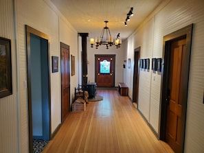 A hallway with wooden floors, a chandelier, framed pictures, and a door with a stained glass window. - Welcoming 2-bedroom house with AC in charming San Simon (San Simon)