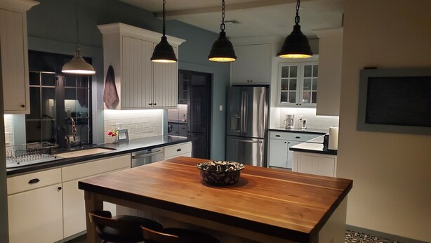 A modern kitchen with a wooden island, pendant lights, stainless steel appliances, and patterned floor tiles. - Welcoming 2-bedroom house with AC in charming San Simon (San Simon)