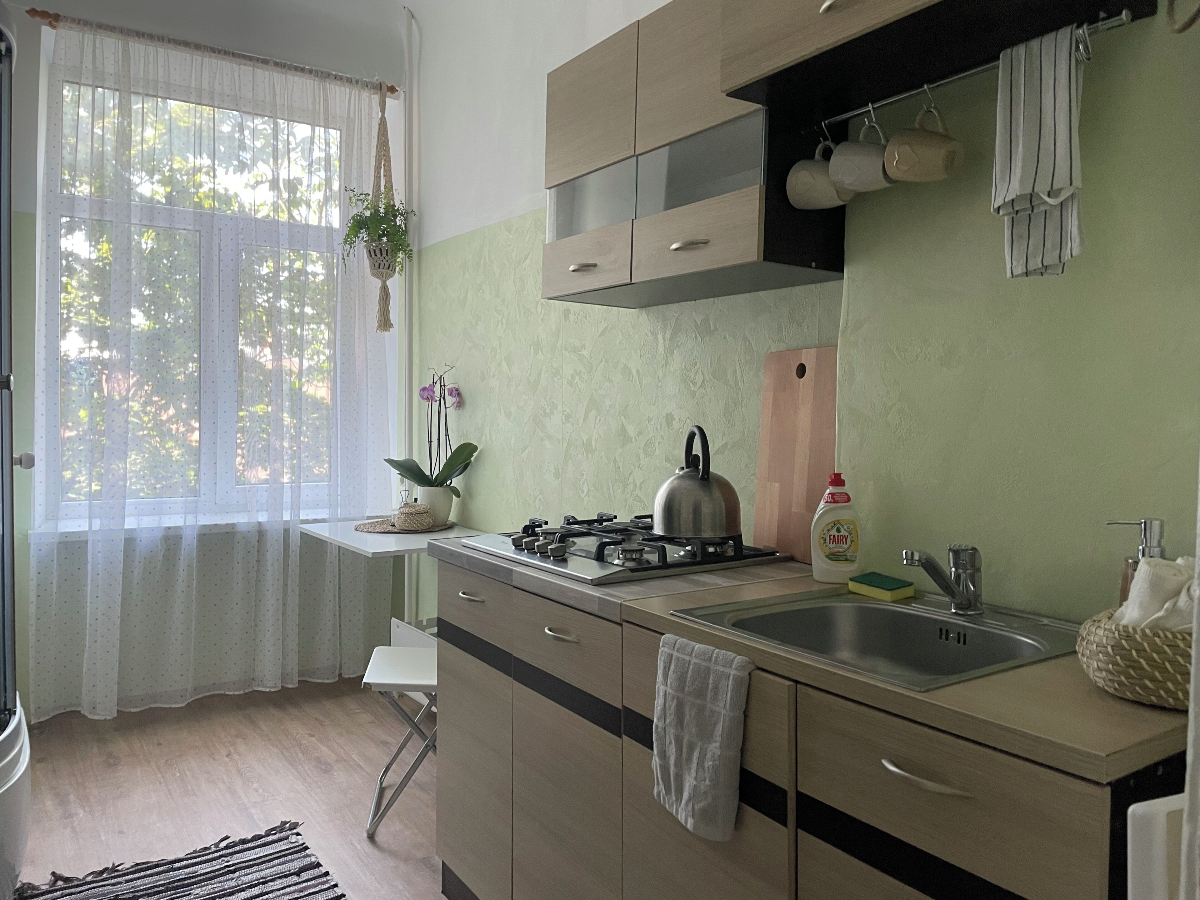 A modern kitchen with a gas stove, stainless steel sink, and wooden cabinets.