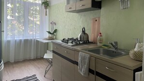 Una cocina moderna con estufa a gas, pileta de acero inoxidable y muebles de madera.