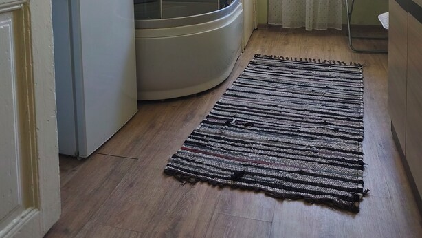 Habitación compacta con ducha, refrigerador, microondas, una mesita y una ventana con cortinas.