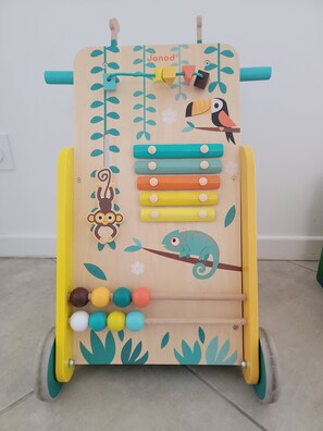 Ein Holz-Lernspielzeug mit Illustrationen von Affe, Chamäleon und Vogel, ausgestattet mit einem Schiebeelement und bunten Bausteinen.