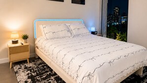 Een slaapkamer met een bed, nachtkastjes, een tapijt met een patroon en wanddecoratie.