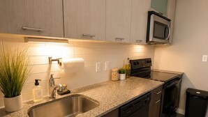 Een moderne keuken met een granieten aanrecht, een roestvrijstalen spoelbak en een ingebouwde magnetron.