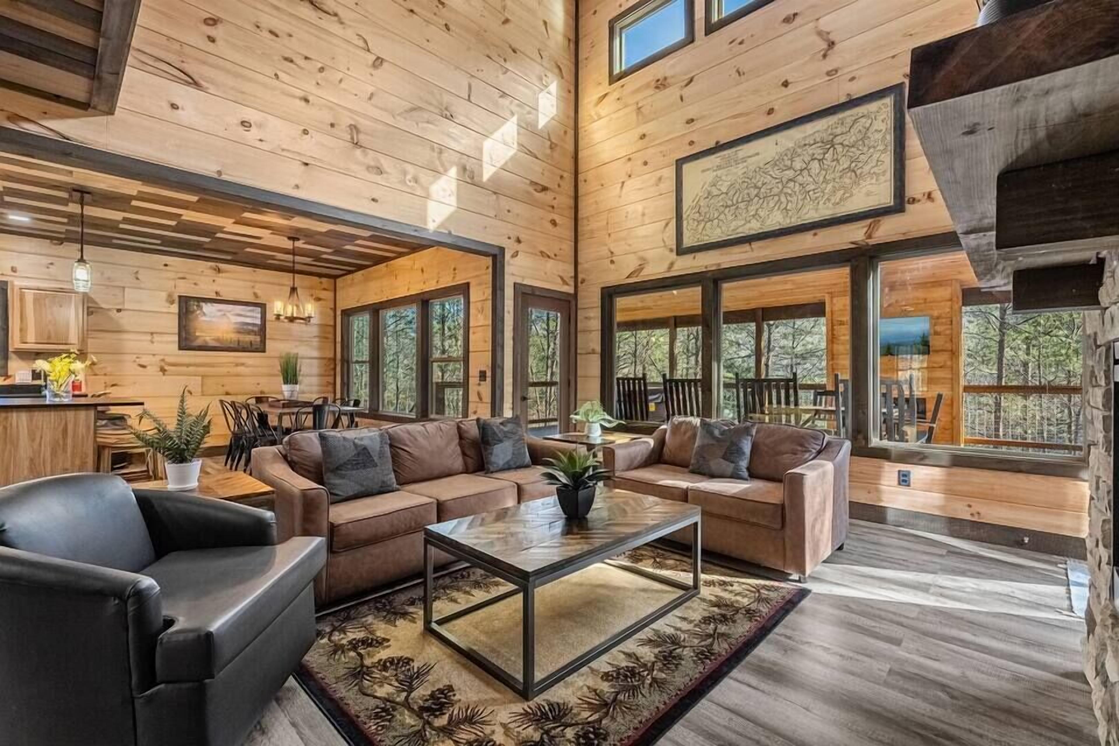 A spacious living area with wooden walls and large windows, a sofa set, and a coffee table.