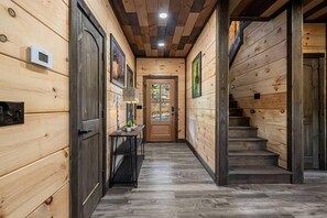 Ein Innenraumflur mit Holzboden, einer Treppe, einer Tür und einem Thermostat an der Wand.