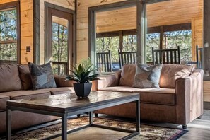 A wooden interior with a sofa and chairs, a coffee table, and a potted plant. - 3-Bedroom Pigeon Forge Cabin with Swim Spa, Hot Tub & Game Loft (Sevierville)