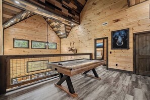Un intérieur en bois avec une table de billard, des fenêtres encadrées et une porte.