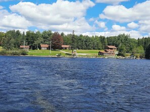 A lakeside property with multiple cabins, a dock, and a forested backdrop. - Lakeview 1 — First Lake Access • 2 Bedrooms • Sleeps 4 • Dock Space • Snowmobile Trail (Pittsburg)