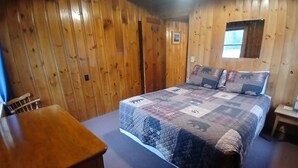 Habitació amb panells de fusta, un llit, una taula petita i una finestra.