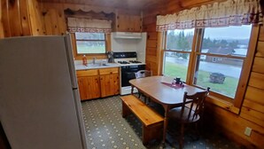 L’intérieur d’une cabane comprend une cuisine, un coin repas et de grandes fenêtres.