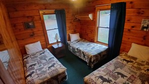 Une cabine avec deux lits en bois, une petite table et une fenêtre.