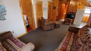 Un salon confortable avec un ensemble de canapés, un téléviseur et un décor intérieur en bois.