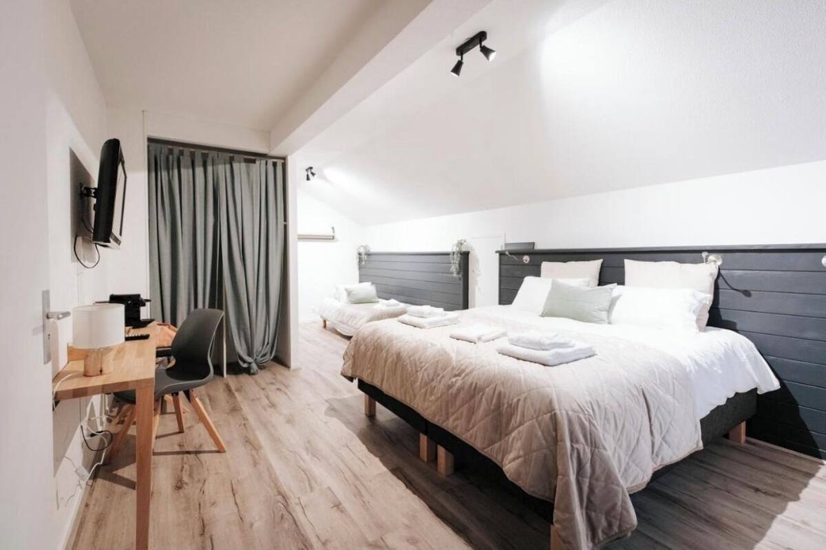 A hotel room with a bed, a desk, a chair, and a TV mounted on the wall.