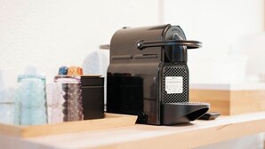 A coffee machine on a wooden counter with a white wall in the background. - Les Loges Du Leman (Crozet)