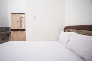 A bedroom with a bed, a wooden wardrobe, and a bathroom with a sink.